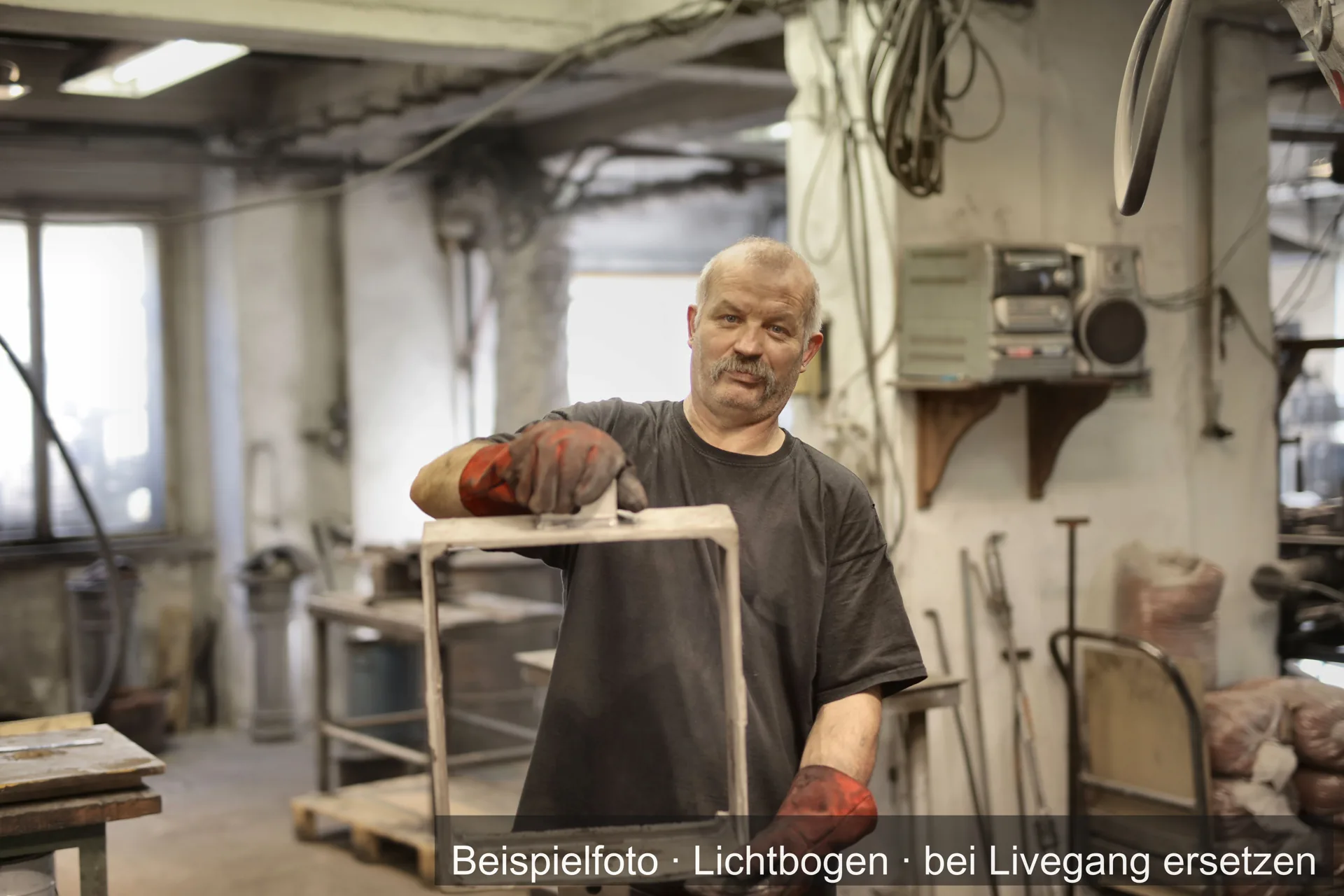 Ein Metallhandwerker mit Schweißerhandschuhen in einer Werkstatt.