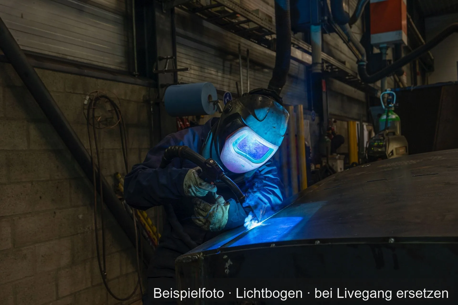 Ein Schweißer mit Helm schweißt an einem Werkstück, Funken am Lichtbogen.